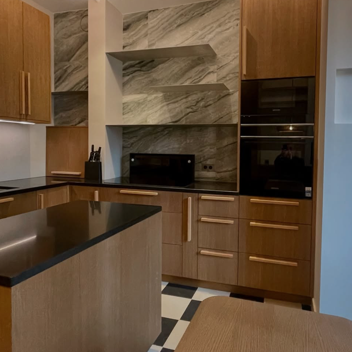 Cuisine moderne rénovée avec îlot central, meubles en bois et plan de travail noir – rénovation intérieure d’appartement par entreprise de rénovation à Paris