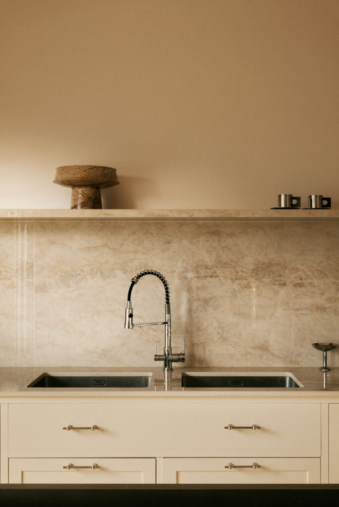 Détail de cuisine après rénovation complète d’appartement à Neuilly-sur-Seine, plan de travail en pierre et robinetterie design